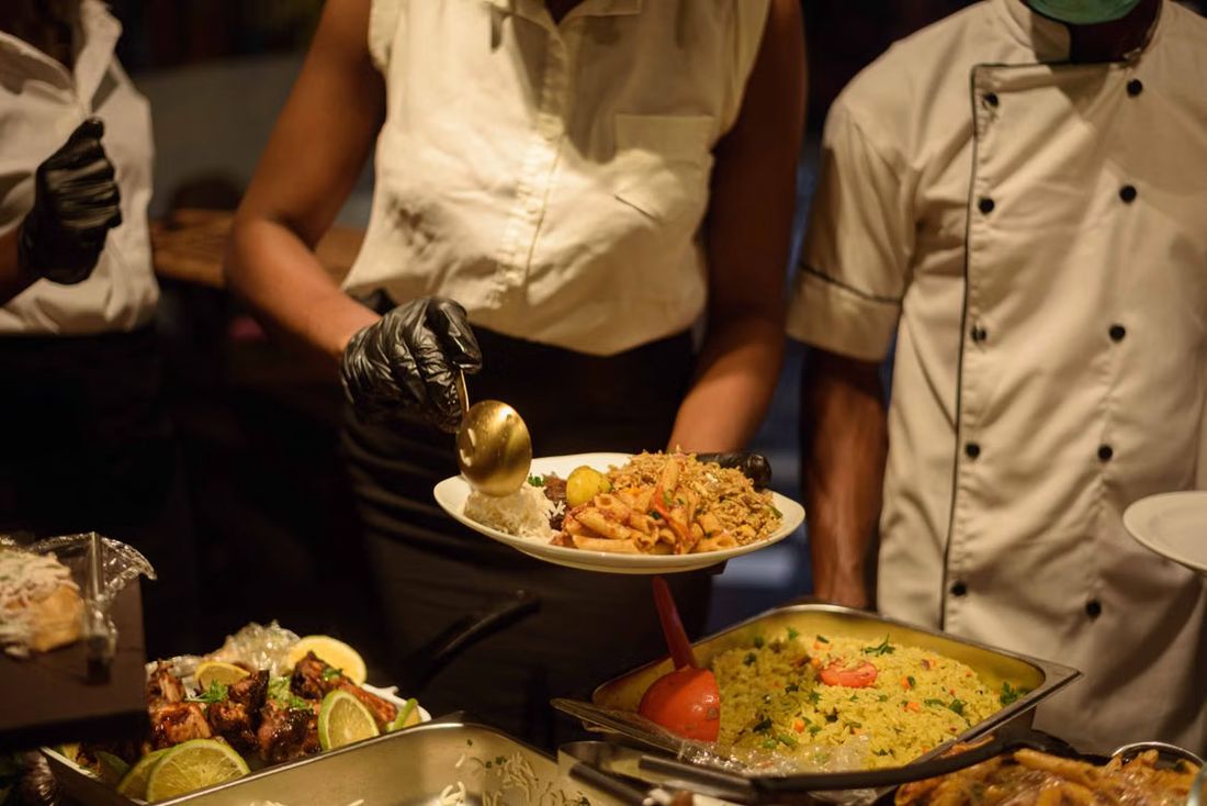 Caterers serving rice, pasta and grilled meat at a buffet