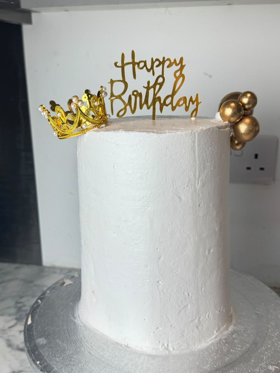 White birthday cake with gold crown topper